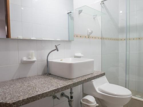 a white bathroom with a sink and a toilet at Margaritas Palace Hotel in Canoa