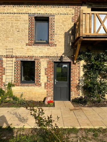 a brick building with a door and a balcony at Gite confortable au milieu des prés - La ferme de Montigny in Neauphe-sur-Dives