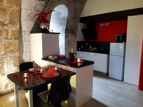 a kitchen with a table and a kitchen with red at Studio avec jacuzzi terrasse amenagee et wifi a Ambrieres les Vallees in Ambrieres Les Vallees