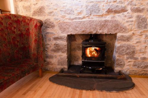 a stone fireplace in a living room with a couch at Schoolhouse in Ballater