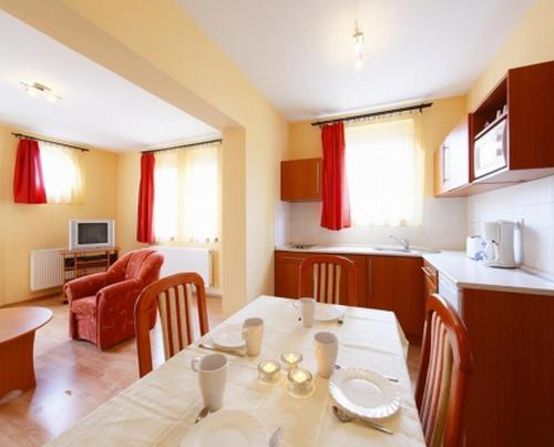 a kitchen and living room with a table and chairs at Centrum Apartmanház in Hévíz