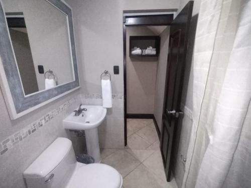 a bathroom with a toilet and a sink and a mirror at L´Aurora Inn hostal in Guatemala