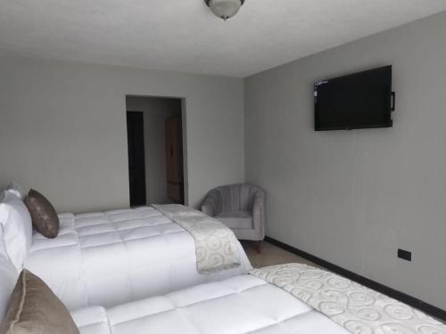 a bedroom with two beds and a flat screen tv at L´Aurora Inn hostal in Guatemala