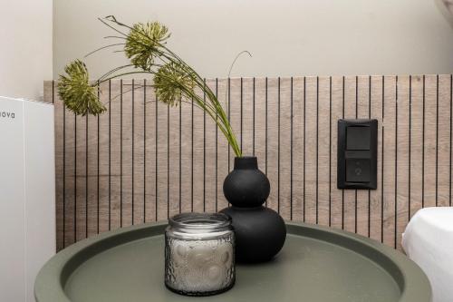 a black vase sitting on a table with a jar at 8 Blocks Apartments in Alexandroupoli
