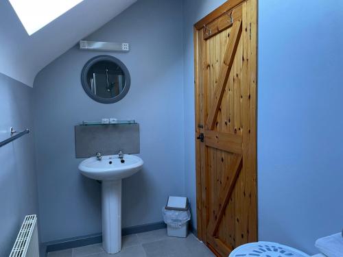 La salle de bains est pourvue d'un lavabo et d'une porte en bois. dans l'établissement Coningbeg Cottage, à Kilmore Quay