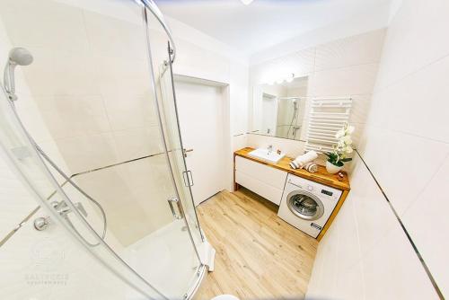 a bathroom with a shower and a washing machine at Apartamenty Bałtyckie - Bulwar Portowy - widok na port, centrum, najlepsza lokalizacja w Ustce in Ustka