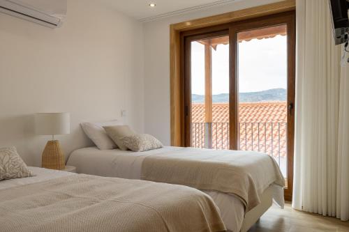 two beds in a white room with a balcony at Casa da Fonte 