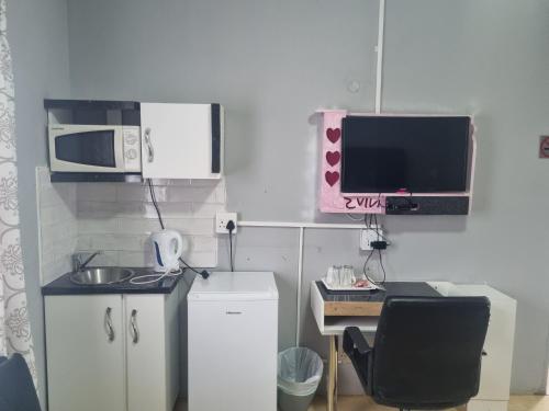 a small kitchen with a desk and a microwave at Home Feeling Guesthouse in Port Shepstone