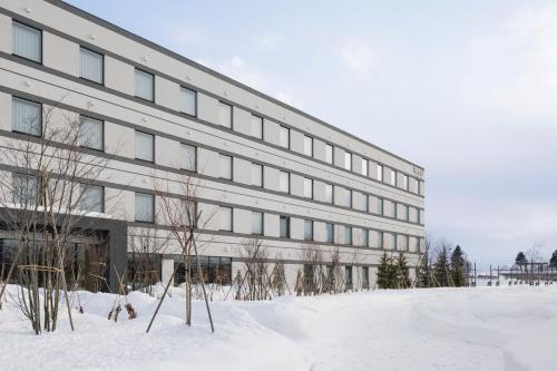 a large building with snow in front of it at Fairfield by Marriott Hokkaido Eniwa in Eniwa