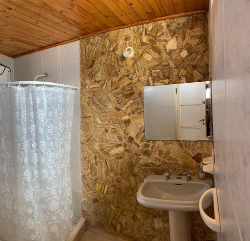 Un baño con lavabo y pared de piedra. en EL SERENO, en San Rafael