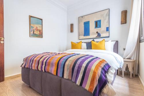 Un dormitorio con una cama con una manta de colores. en Caprice palace hivernage en Marrakech