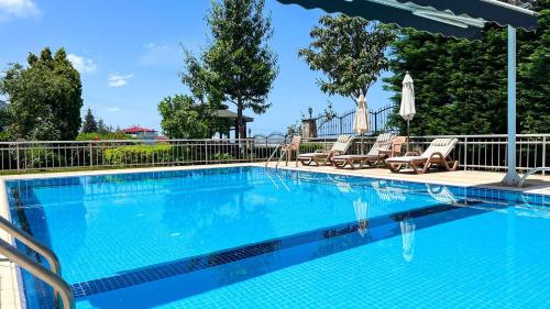a large swimming pool with chairs and a fence at Heaven White Palace in Bostancı