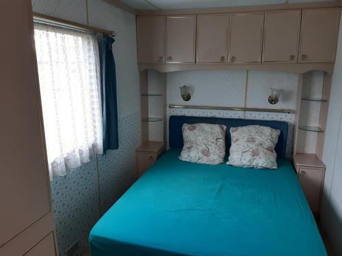 a small bedroom with a blue bed with two pillows at Le Mandala in Plazac
