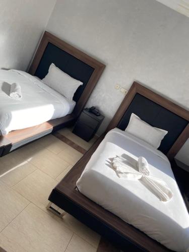 two twin beds in a room withskirts at AMWAJ HOTEL in El Jadida