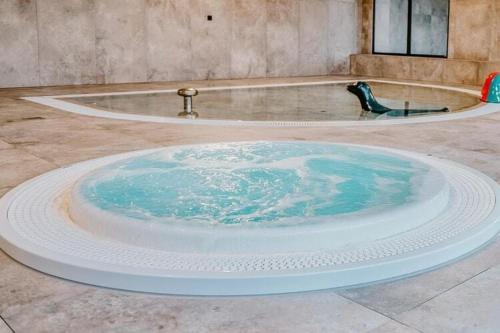 a large bath tub with blue water in the middle at Comfortable apartment, swimming pool, sauna, fitness, Dziwnów in Dziwnów