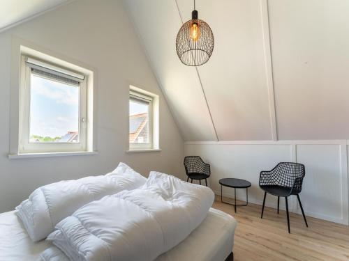 1 dormitorio con 1 cama blanca y 2 sillas en Pleasant holiday home in Scherpenisse with garden en Scherpenisse