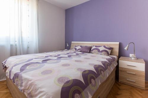 a bedroom with a large bed with purple walls at Olive Hill Apartment in Portorož