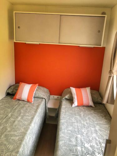 two beds in a small room with an orange wall at Corte Attilea in Valeggio sul Mincio