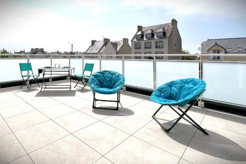 un patio avec des chaises et une table sur un toit dans l'établissement Le Grand Large-Appart proche mer avec terrasse, à Brignogan-Plage
