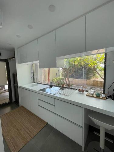 eine weiße Küche mit einem Waschbecken und einem Fenster in der Unterkunft Charming Coastal Retreat in Anavyssos