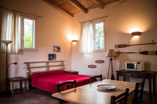 Tenuta Valdelmelo في كاستيغليون ديلا بيسكايا: غرفة نوم بسرير احمر وطاولة وكراسي