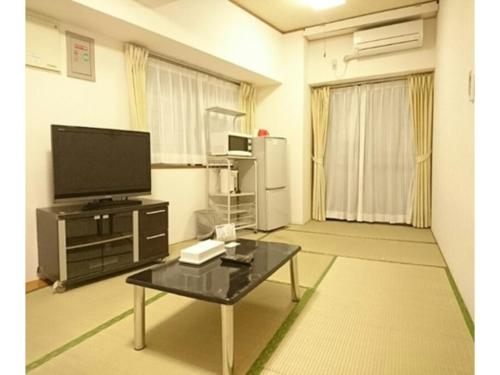 Kokusai Towns Inn - Vacation STAY 35424v في ناها: غرفة معيشة مع تلفزيون وطاولة قهوة