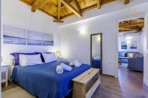 a bedroom with a large bed with blue sheets and wooden ceilings at Margini's Country House in Panormos Skopelos