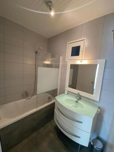 La salle de bains est pourvue d'un lavabo vert et d'une baignoire. dans l'établissement Appartement Cosy Avec Terrasse Parking Proche Plages et Calanques, à Marseille