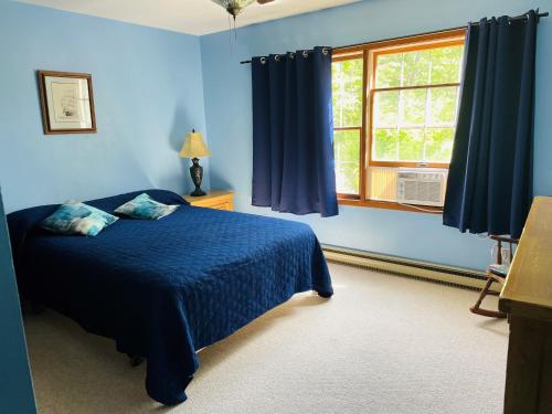 a blue bedroom with a bed and a window at Parkside Inn in Ellison Bay