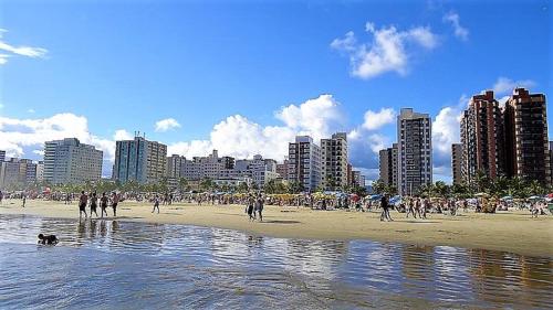 un grupo de personas caminando por la playa en Pousada Primeira Quadra Da Praia, en Praia Grande