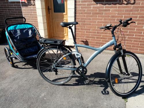 un vélo garé à côté d'un bâtiment avec une poussette dans l'établissement Gîte du Cluse, à Éperlecques