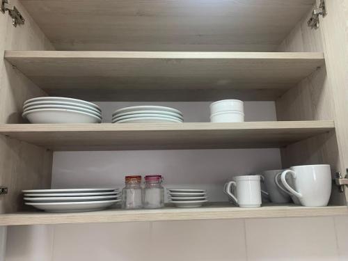 - une étagère avec des assiettes, des tasses et des tasses dans l'établissement AIKA Monoambientes, à Salta