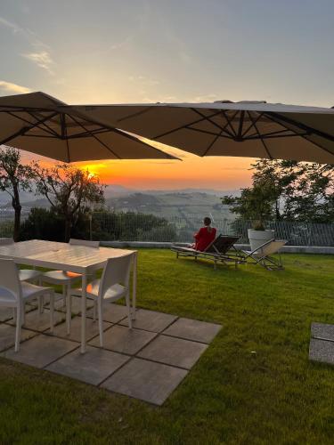 una persona seduta su una panchina sotto un ombrello di Tramonto - Le Grotte Rooms & Apartments a Camerano