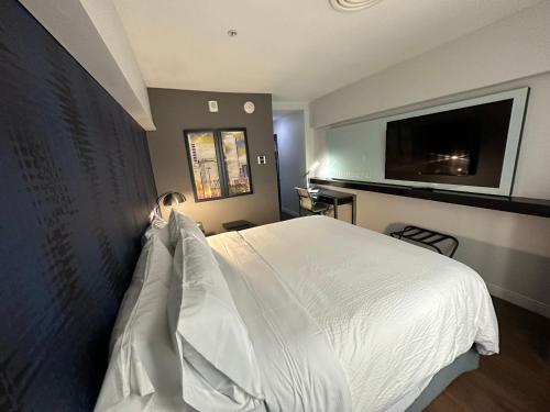 a bedroom with a bed with white sheets and a flat screen tv at Holiday Inn Express - Dallas Downtown by IHG in Dallas