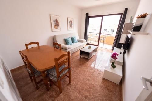 una sala de estar con una mesa y un sofá en SUN BAY, en Caleta de Fuste