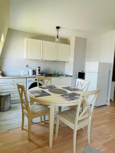 une cuisine avec une table et des chaises dans une cuisine dans l'établissement Appart Cosy 2 chambres, à Bruz