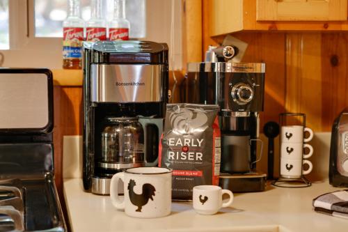 a counter with a coffee maker and cups on it at 3 Mi to Big Trees State Park Cabin with Scenic Deck in Arnold