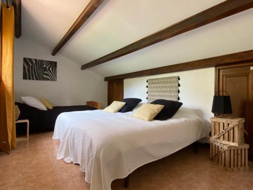 - une chambre avec un grand lit blanc et un canapé dans l'établissement Cases des oliviers, à Cases-de-Pène