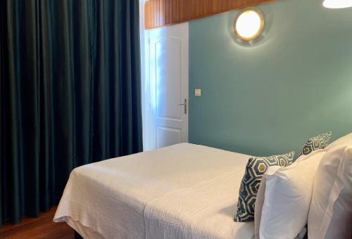a bedroom with a bed and a window with blue curtains at Hotel l'Impératrice in Fort-de-France