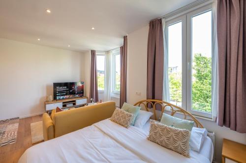 a bedroom with a bed and a couch and windows at The Bohemian Palace in Vilvoorde