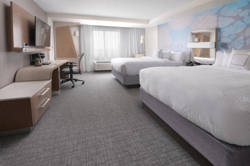 a hotel room with two beds and a desk at Courtyard by Marriott Austin Pflugerville in Pflugerville