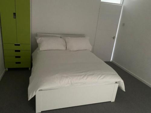 a white bed with white pillows and a green cabinet at Beautiful-2 bedroom Apartment, 1 bathroom, sleeps 6, in greater london (South Croydon). Provides accommodation with WiFi, 3 minutes Walk from Purley Oak Station and 10mins drive to East Croydon Station in Purley