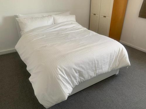 un letto bianco con lenzuola e cuscini bianchi di Beautiful-2 bedroom Apartment, 1 bathroom, sleeps 6, in greater london (South Croydon). Provides accommodation with WiFi, 3 minutes Walk from Purley Oak Station and 10mins drive to East Croydon Station a Purley