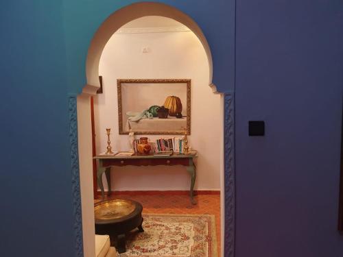 un couloir avec une table et une porte bleue dans l'établissement Dar Anneke, à Chefchaouen