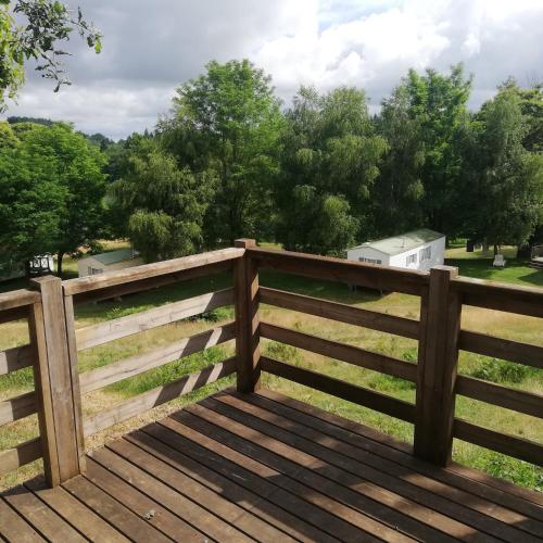 une clôture en bois avec des arbres en arrière-plan dans l'établissement camping la rivière, à Vabre-Tizac