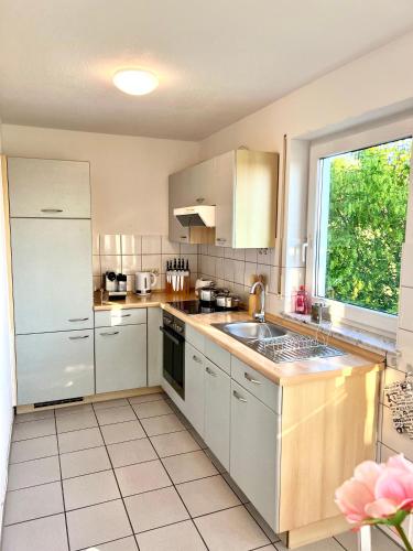 a kitchen with white cabinets and a sink and a window at Panorama Domizil Ravensburg mit Alpenblick Balkon in Ravensburg
