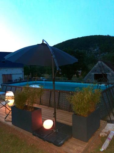 - une terrasse avec un parasol à côté de la piscine dans l'établissement P'tit cocon au cœur du Lot avec piscine, à Dégagnac