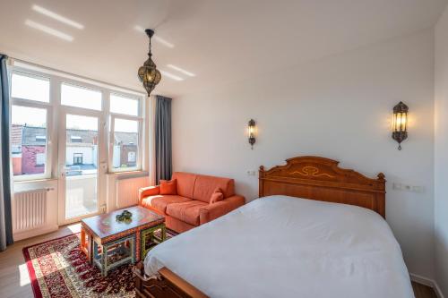 a bedroom with a bed and a chair and a window at Le Petit Riad in Vilvoorde