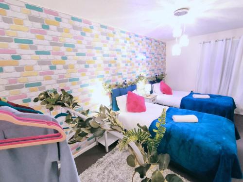 um quarto com 2 camas com almofadas azuis e cor-de-rosa em Bakerville Stays - Home in Osier - 3 Bed em Nottingham