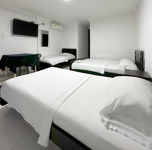 a hotel room with two beds and a table and chairs at Hotel Costa Caribe in Barranquilla